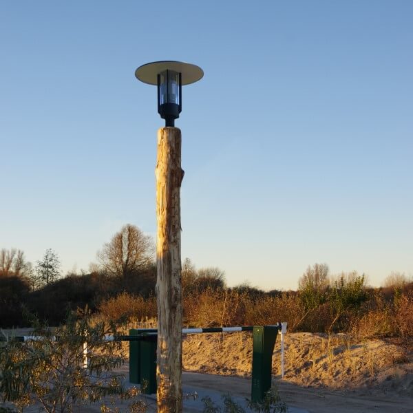 Wooden light pole with a round fixture near the dunes