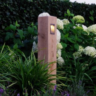 Wooden path lighting with black fixture next to hydrangea